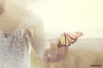Bild på A butterfly leans on a hand of a girl in the middle of nature